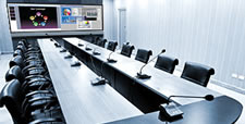 Boardroom with large table, video screens on far wall